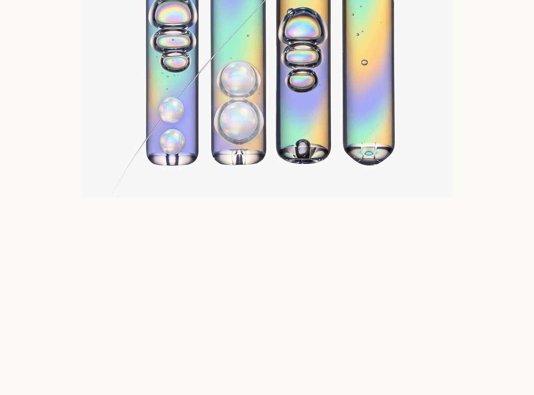 Laboratory tubes containing iridescent liquids and bubbles.